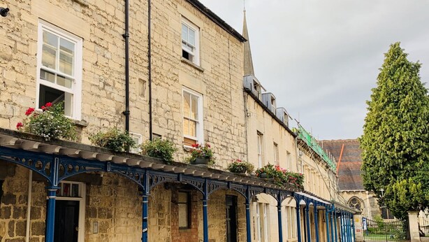 A stone building with a covered walkway and flower boxes. - Windows Over Stroud Penthouse apartment with views (Stroud)
