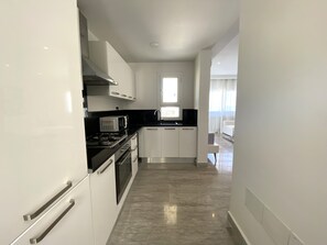 A modern kitchen with white cabinets, a black countertop, and stainless steel appliances. - Le Relais: Apt de luxe à 5mn de la marsa (La Marsa)