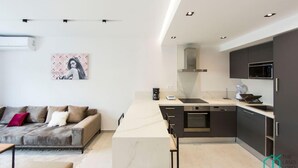 A modern kitchen with dark cabinetry, a marble countertop, and a built-in oven. - Sunset 204 Luxury 2bds with Gym (Tunis)