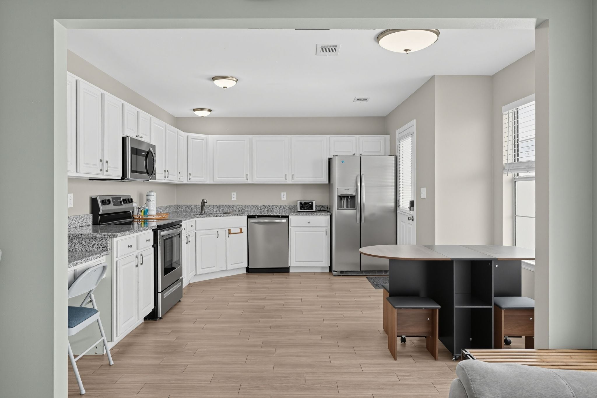 Una cocina moderna con armarios blancos, electrodomésticos de acero inoxidable y piso de madera.
