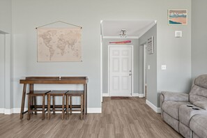 Een kamer met een houten bankje, een wereldkaart, een deur en een bank.