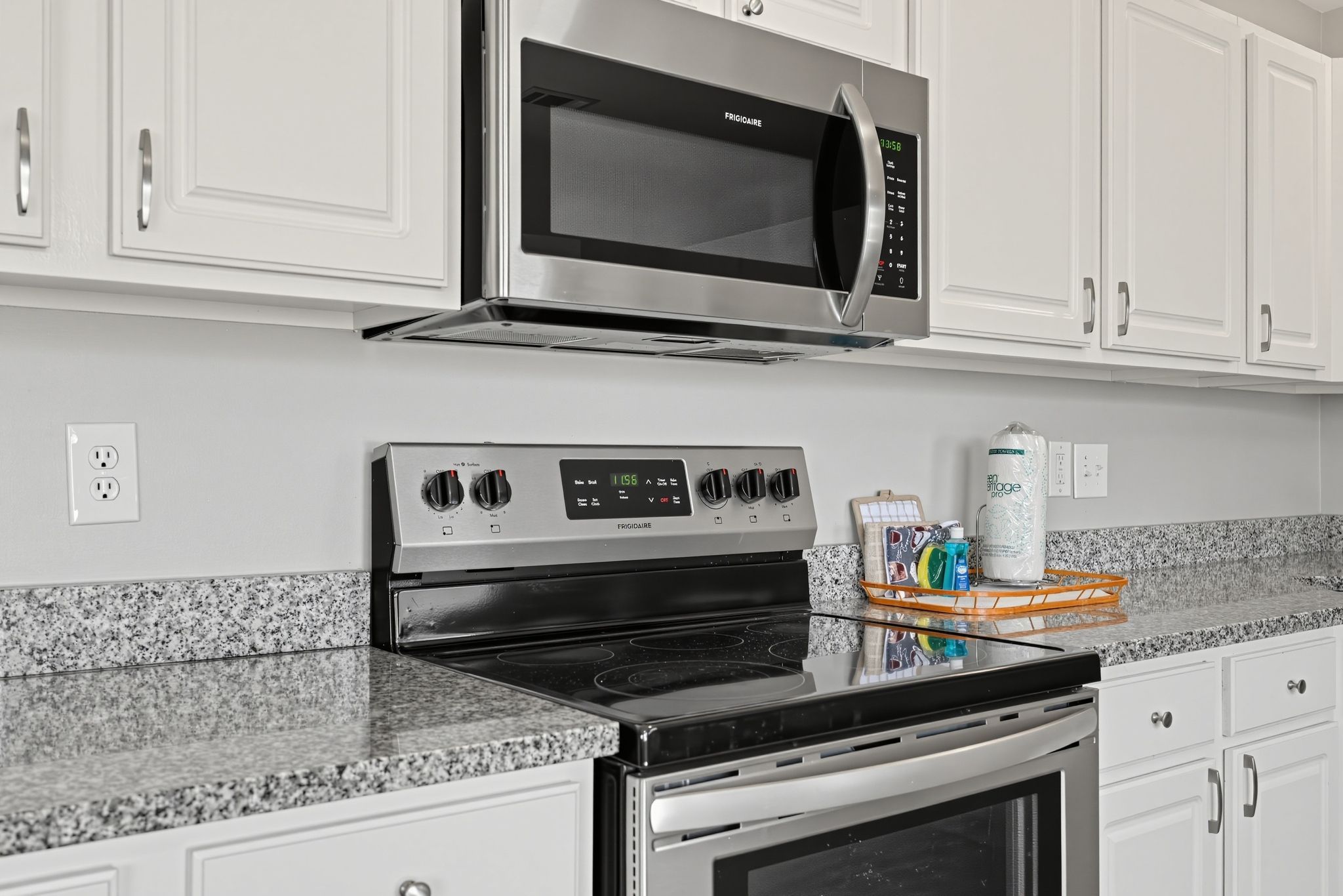 A kitchen with a stainless steel microwave, a stove, and a refrigerator.