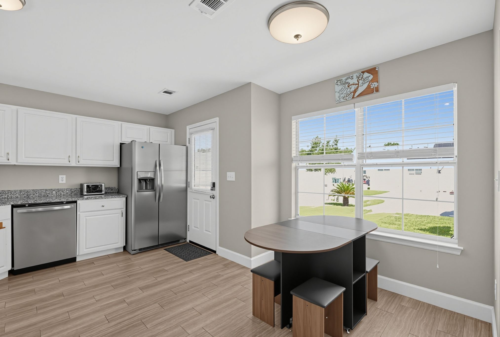 Kitchen dining nook with compact table and stools next to a bright window.
