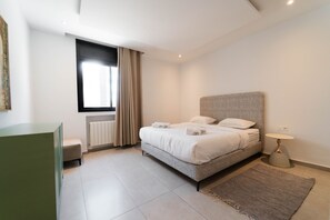 A modern bedroom with a bed, bedside table, and a window with curtains. - SUNSET 201: Luxury 2bds with gym (Tunis)