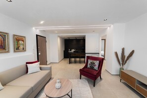 A modern living room with a sofa, armchair, coffee table, and a dining area with a table and chairs. - SUNSET 201: Luxury 2bds with gym (Tunis)