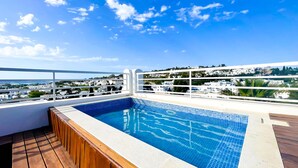 Una piscina en la azotea con vistas despejadas del paisaje urbano y una terraza de madera.