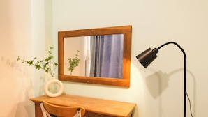 A wooden desk with a mirror, a chair, a floor lamp, and a small plant. - NHA NGHI AO (Ho Chi Minh City)