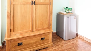 A wooden wardrobe with two doors and a small refrigerator with a carton of milk on top. - NHA NGHI AO (Ho Chi Minh City)