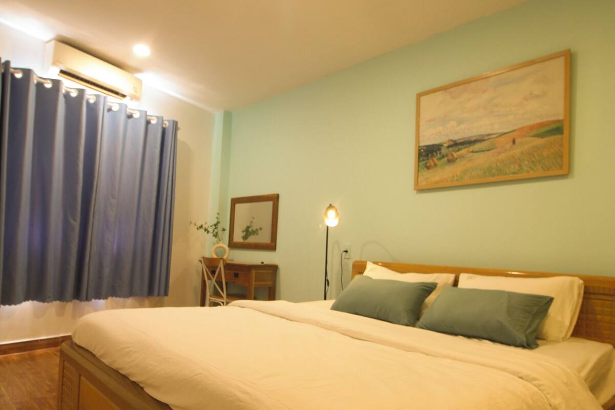 Un dormitorio con una cama de madera, un escritorio, una silla, una lámpara y un cuadro en la pared.