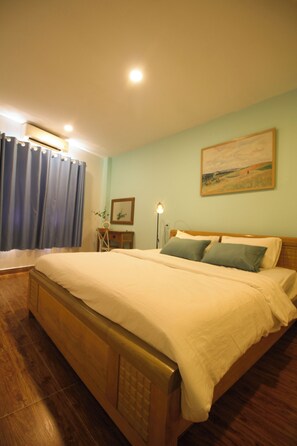Une chambre à coucher avec un lit en bois, un bureau, une chaise, une lampe et un tableau au mur.