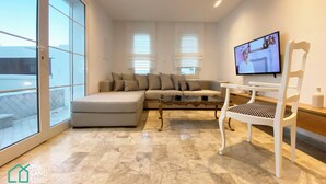 A modern living room with a sofa, a coffee table, and a TV mounted on the wall. - New 1 bd with garden and sea side at Marsa Cornich (Site archéologique de Carthage)