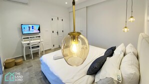 A bedroom with a bed, a desk, a television, and a hanging light fixture. - New 1 bd with garden and sea side at Marsa Cornich (Site archéologique de Carthage)