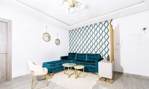 A modern living room with a teal sectional sofa, a white armchair, and a small round coffee table. - New 1bd with swimming pool 5mn to Lac & Carthage (Ain Zaghouan)