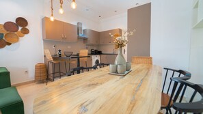 Eine moderne Küche mit einer zentralen Kochinsel, integrierten Geräten und einem Essbereich mit langem Tisch und Stühlen.
