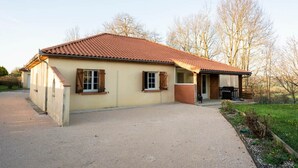 A single-story building with a tiled roof, a covered porch, and a gravel driveway. - A Getaway in the Pyrenees: Views, Hot Tub, and Forest (Marseillan)