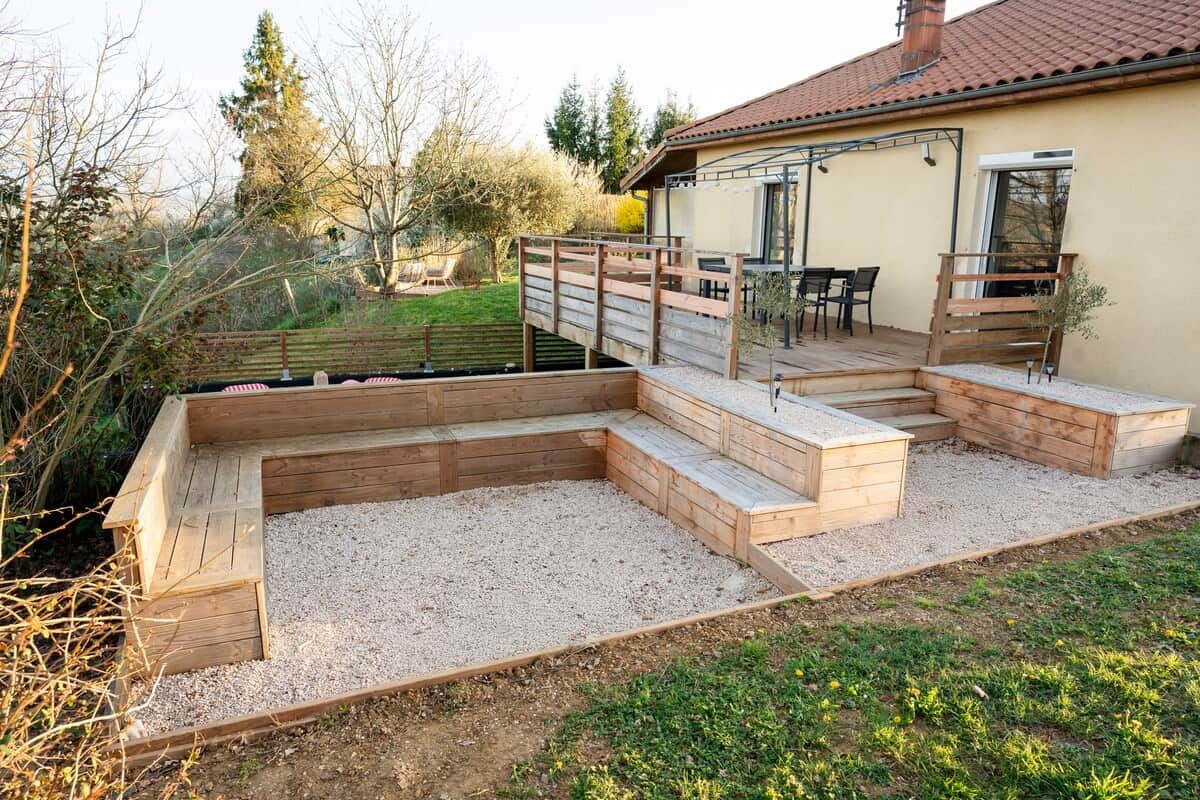 Une maison dotée d’une terrasse en bois, d’un patio et d’un jardin.