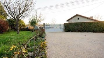 A gravel driveway leading to a gated entrance with a building on the right.