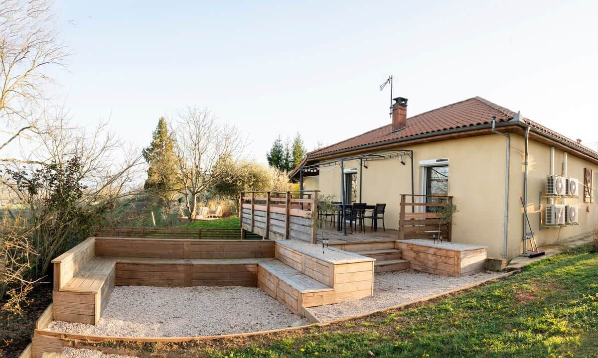 Een huis met een terras, tuinmeubels buiten en een tuin.