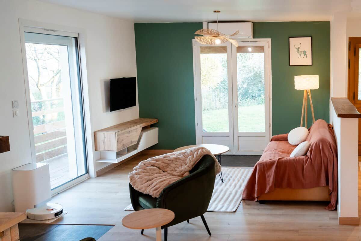 Ein modernes Wohnzimmer mit einer Couch, einem Sessel, einem kleinen Tisch und einem Fernseher an der Wand.