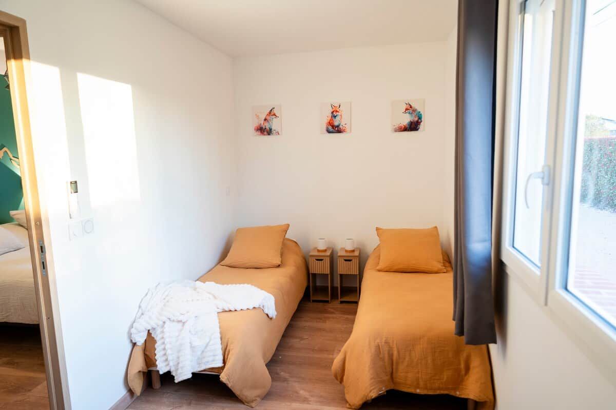 Una habitación con dos camas, una ventana y obras de arte en la pared.