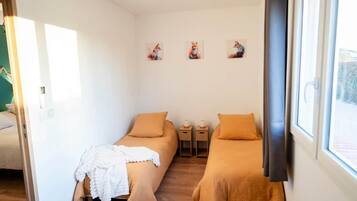 Una habitación con dos camas, una ventana y obras de arte en la pared.