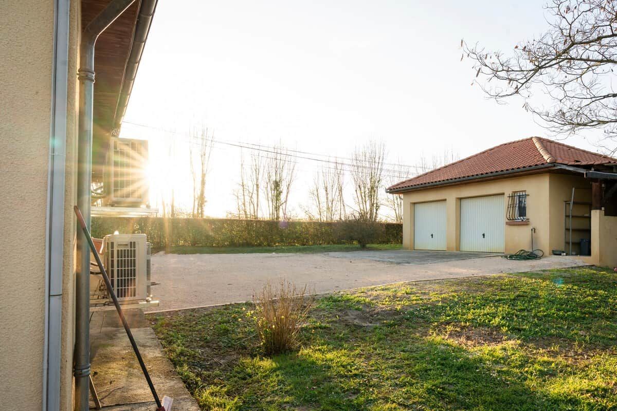 A building with a garage, a small garden, and a clear sky.