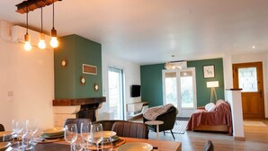 A dining area with a table set for four, a sofa, and a television in the background. - A Getaway in the Pyrenees: Views, Hot Tub, and Forest (Marseillan)