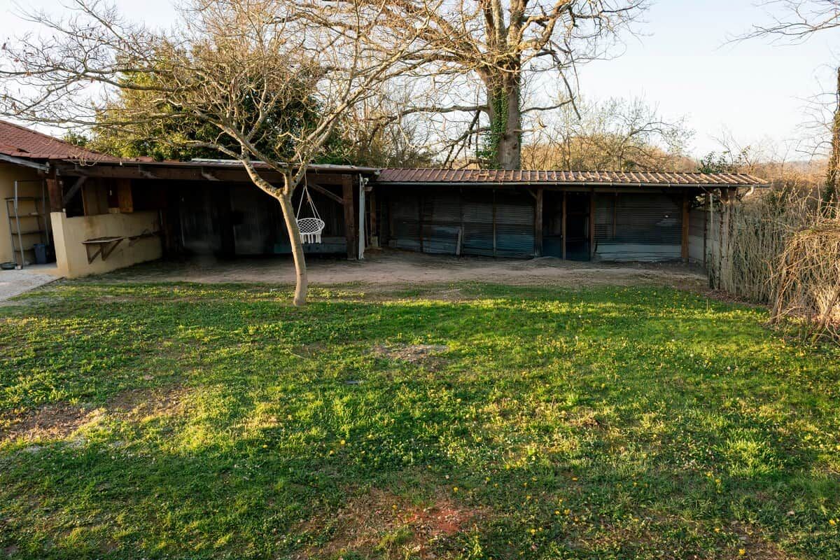 A residential property with a detached house, a covered garage, and a grassy yard.