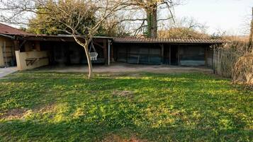 A residential property with a detached house, a covered garage, and a grassy yard.