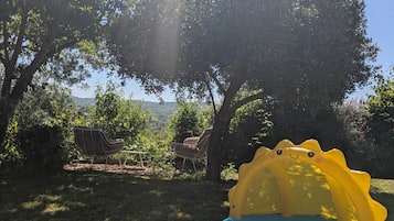 Ein aufblasbarer Pool mit Hai-Motiv, umgeben von Bäumen und einer Rasenfläche mit Picknickplatz.