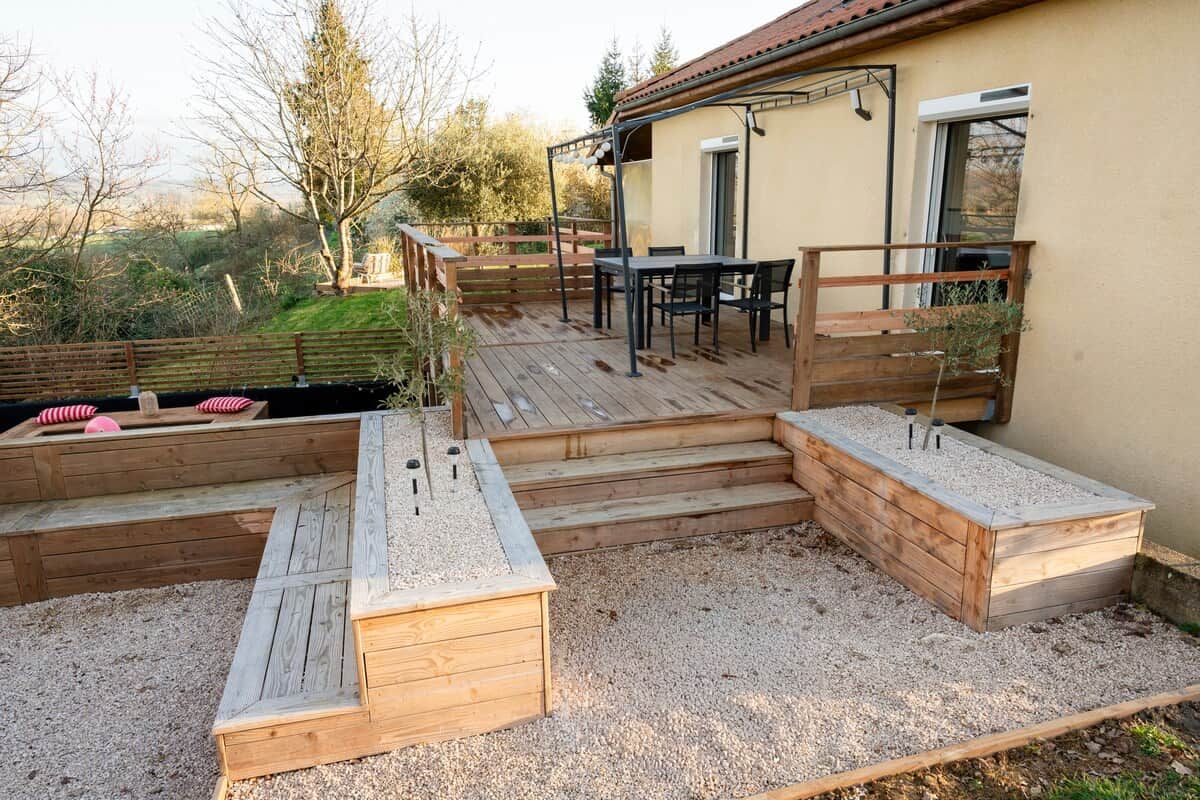 En terrasse med et bord og stole, træplantere og udsigt over landskabet.
