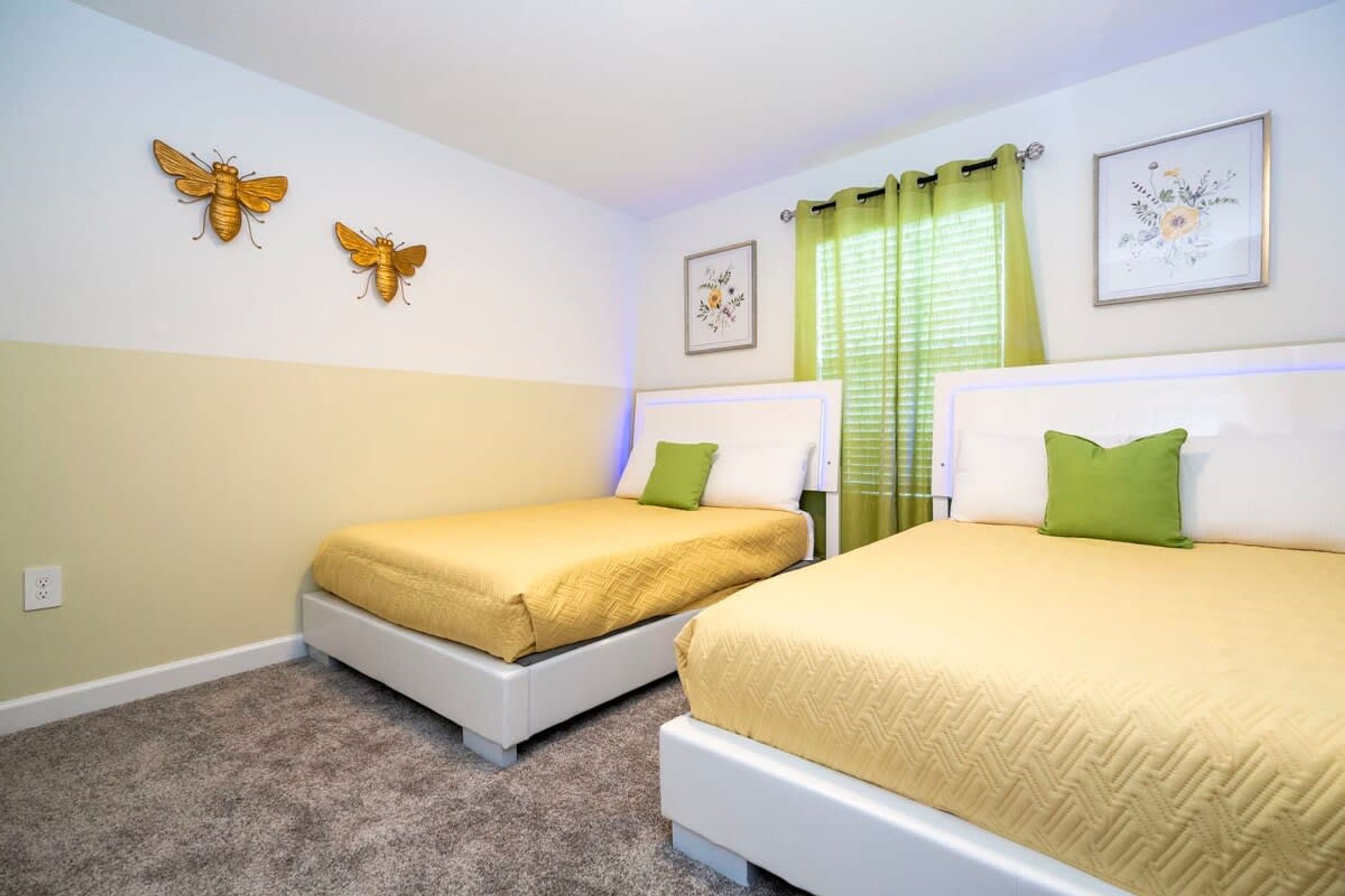 A hotel room with two beds, a green curtain, and wall art.