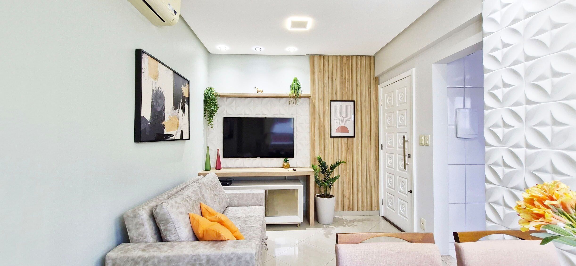 A living room with a sofa, TV, and decorative plants.