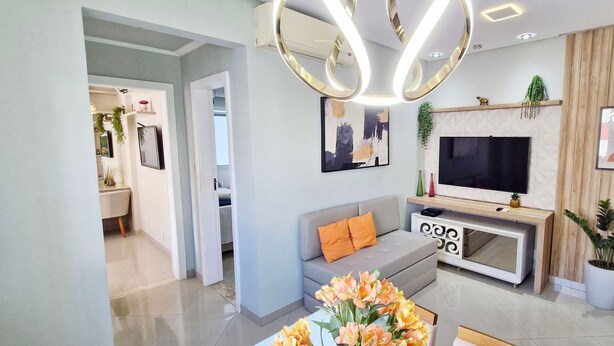 A modern living room with a sofa, TV, and decorative plants. - COBAR0148 - Edifício Beta (Salvador)
