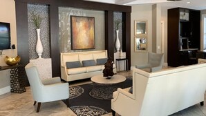 Una sala de estar moderna con un sofá, sillones, una mesa de centro y un cuadro abstracto grande.