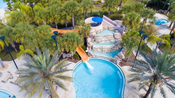 Un resort con varias piscinas, palmeras y un tobogán de agua.