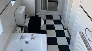 A bathroom with a checkered floor, a bathtub, a toilet, a shower, and a mirror. - Serene 3-bedroom cottage in lovely Pocklington perfect for relaxing (Pocklington)