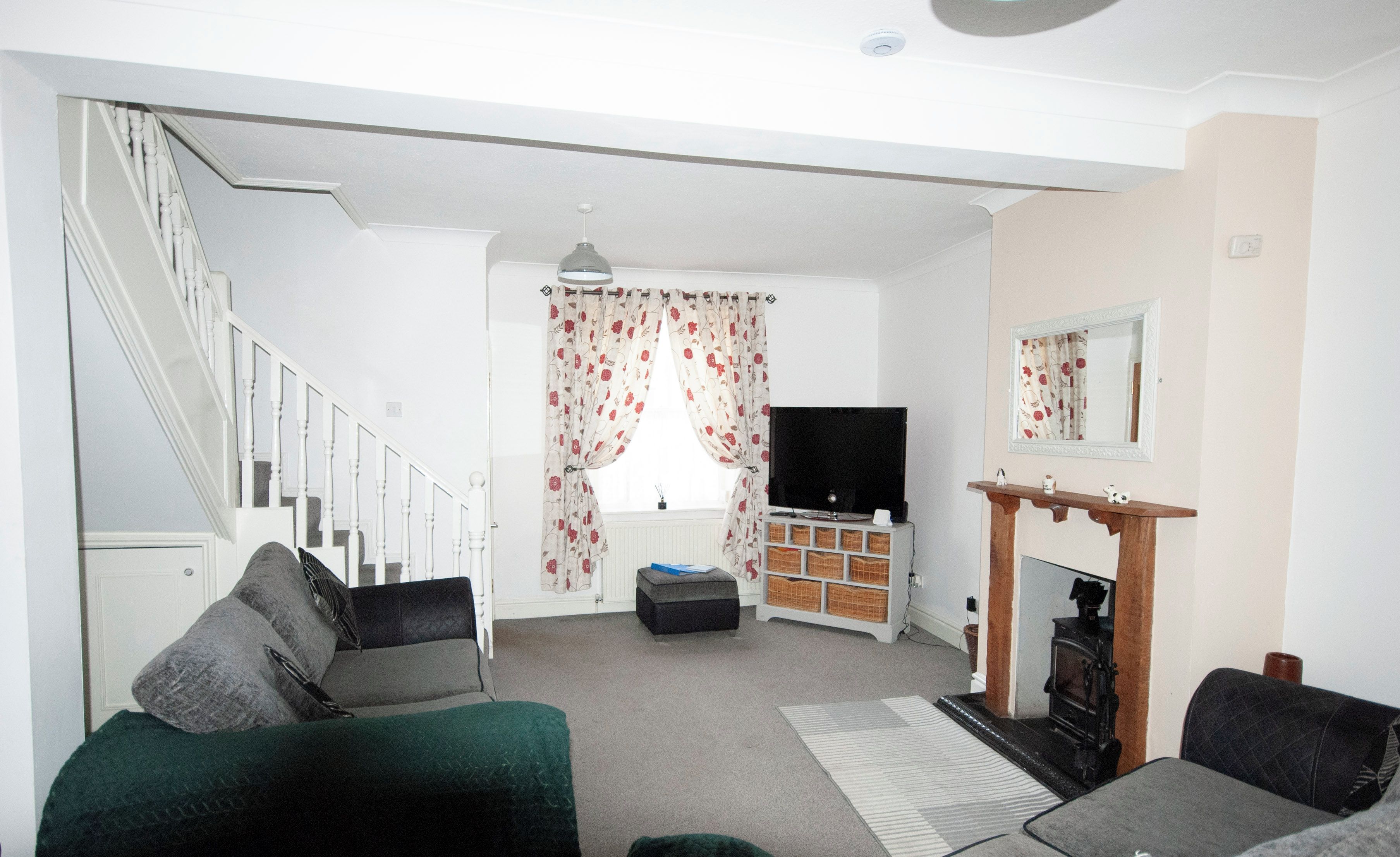 A living room with a staircase, a fireplace, a television, and a sofa.
