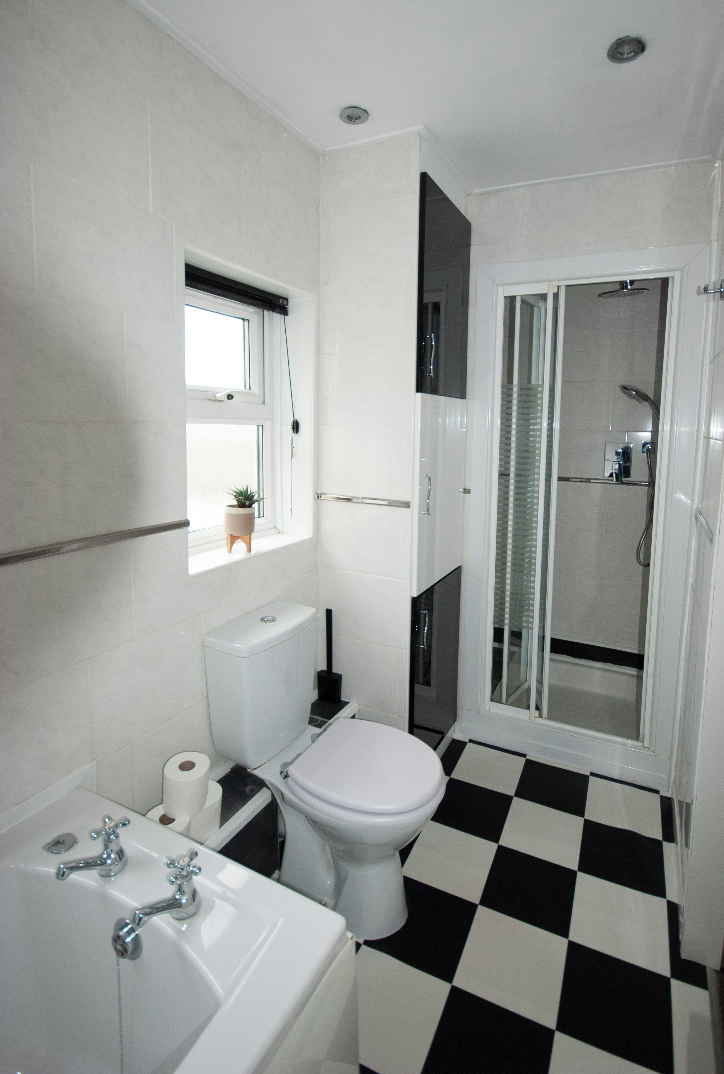 Et badeværelse med toilet, vask og brusebad.