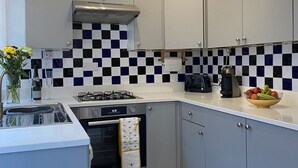 A modern kitchen with grey cabinets, a checkered backsplash, a gas stove, and a coffee maker. - Serene 3-bedroom cottage in lovely Pocklington perfect for relaxing (Pocklington)