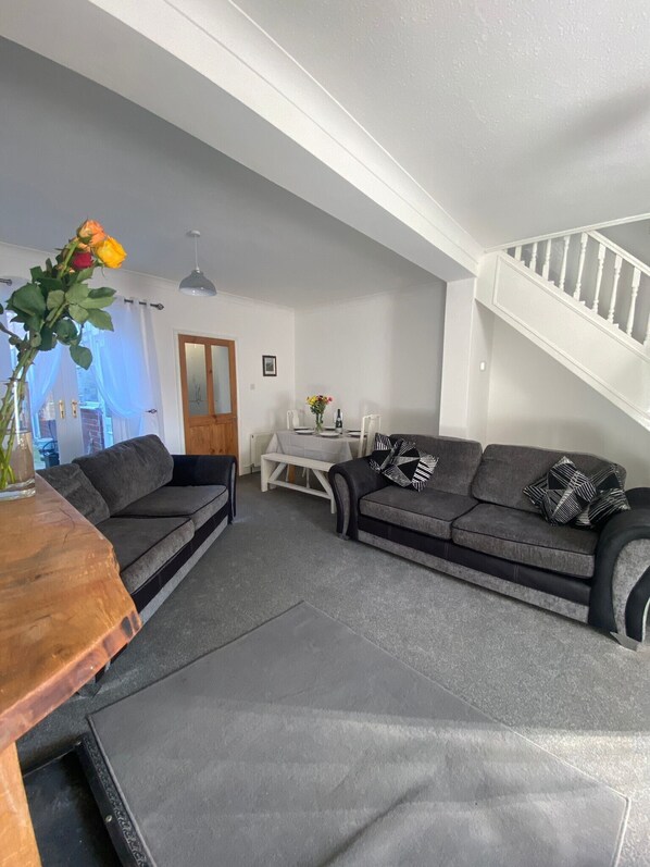 A modern living room with grey sofas, a wooden coffee table, and a staircase.