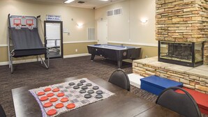 Ett rum med ett biljardbord, ett fotbollsspel och ett shuffleboard-bord.