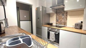 A modern kitchen with stainless steel appliances, a wooden countertop, and a patterned backsplash. - Luxurious studio room in the heart of East Kilbride 10mins from a hospital (East Kilbride)