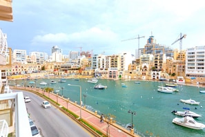 Un puerto deportivo con barcos, un paseo marítimo y edificios con grúas de construcción.