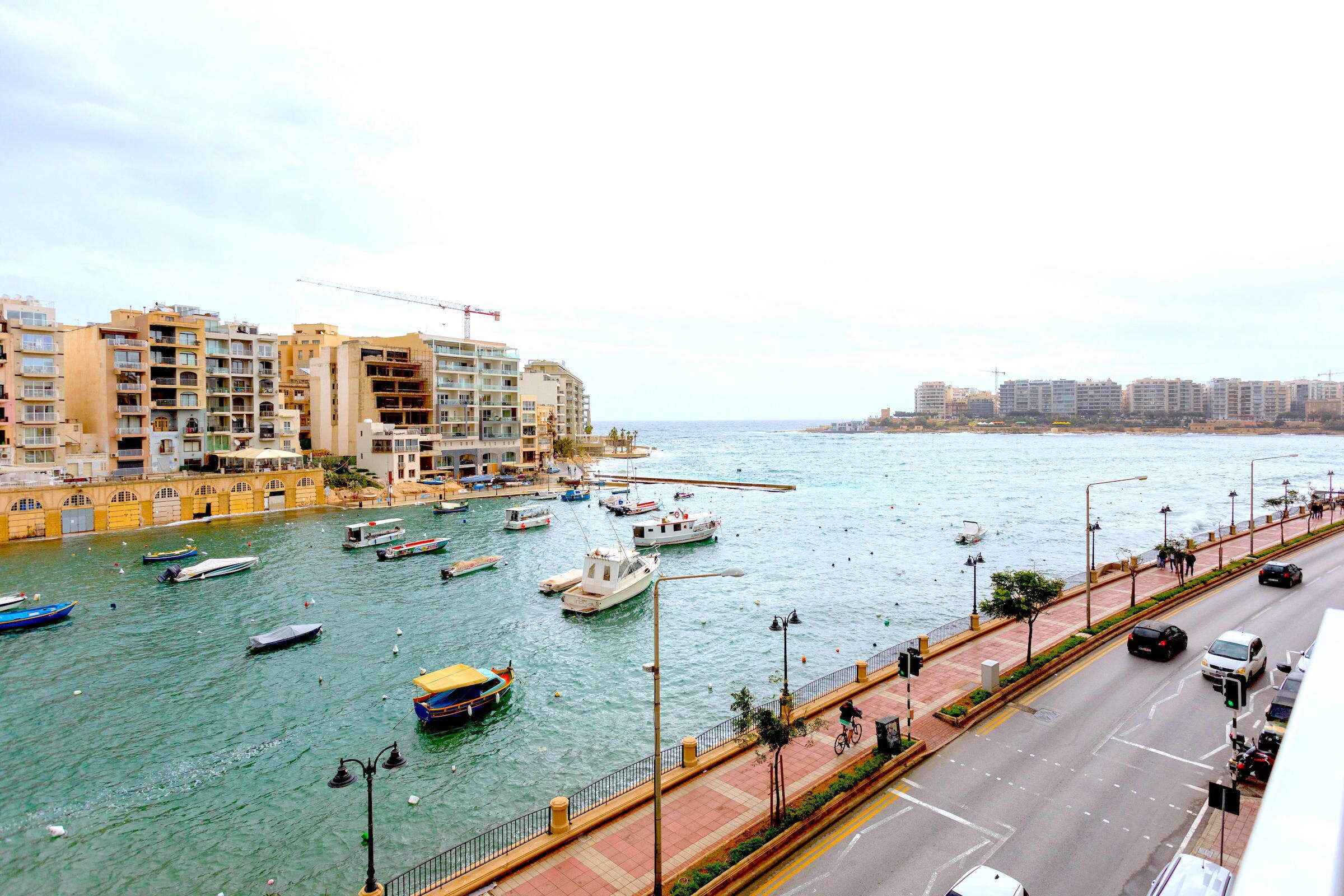 Un port de plaisance avec des bateaux, une promenade en bord de mer et des immeubles d’habitation.