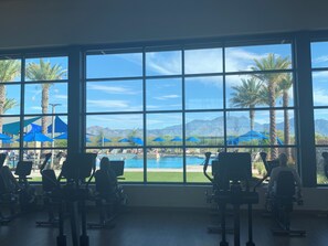 A gym with exercise equipment and a view of a pool and mountains through large windows. - AVAIL SEP 10 - OCT 5! Elegant Quail Creek Resort Home with Spool, Green Valley (Green Valley)