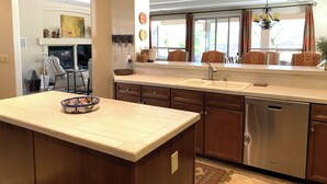 A kitchen with a central island, stainless steel dishwasher, and a window with curtains. - Elegant Quail Creek Resort Home with Spool, in Green Valley near Tucson (Green Valley)
