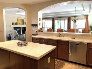 A kitchen with a central island, stainless steel dishwasher, and a window with curtains. - Elegant Quail Creek Resort Home with Spool, in Green Valley near Tucson (Green Valley)