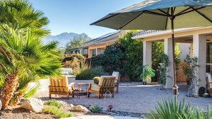 An outdoor patio area with a covered seating area, a fire pit, and a variety of plants and rocks. - Elegant Quail Creek Resort Home with Spool, in Green Valley near Tucson (Green Valley)