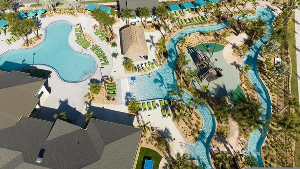 Vista aérea de um resort com várias piscinas, áreas de descanso e palmeiras.